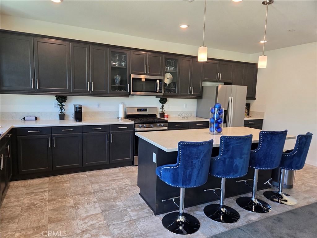 7900 Raincross Court Riverside, CA 92507 - Photo 14 of 21 a kitchen with stainless steel appliances a sink a stove a refrigerator cabinets and a dining table