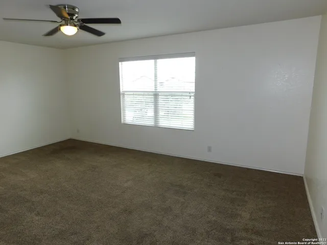 an empty room with a window and a fan