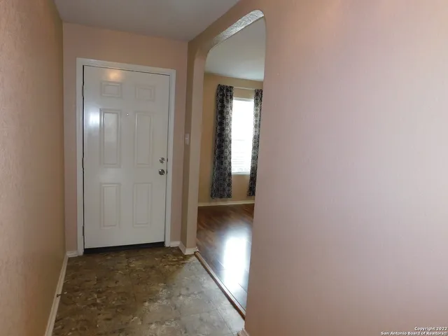 a view of a hallway with wooden floor and a bathroom