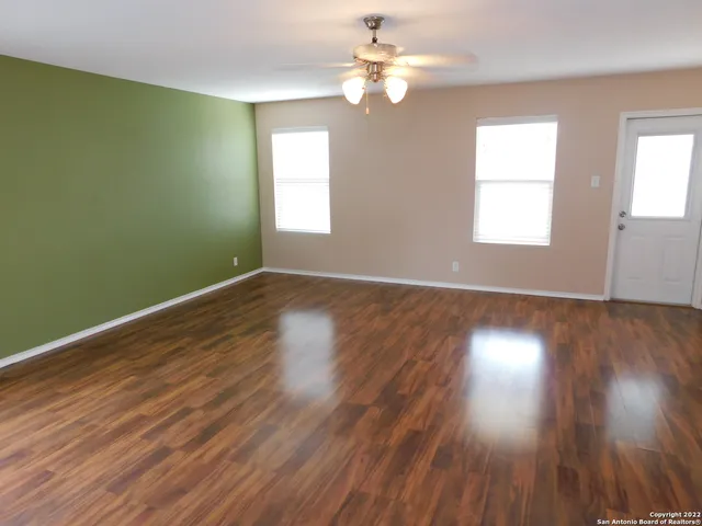 a view of empty room with wooden floor and fan