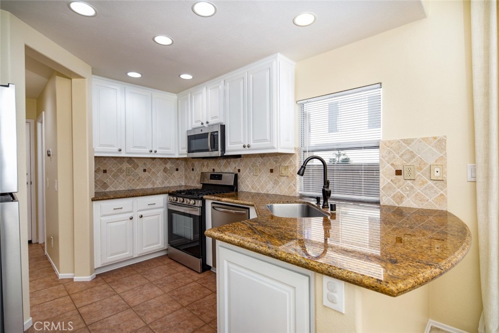 1 Quebec Aliso Viejo, CA 92656 - Photo 8 of 40 a kitchen with kitchen island granite countertop a sink a stove and white cabinets