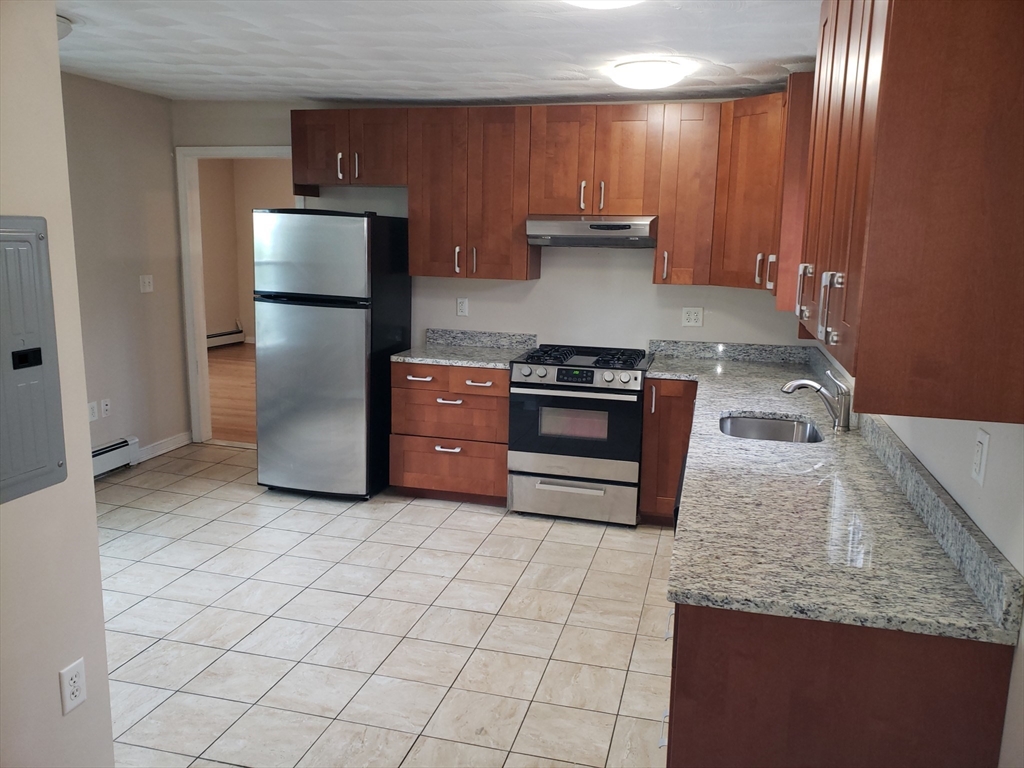 a kitchen with kitchen island granite countertop a stove a sink and a refrigerator