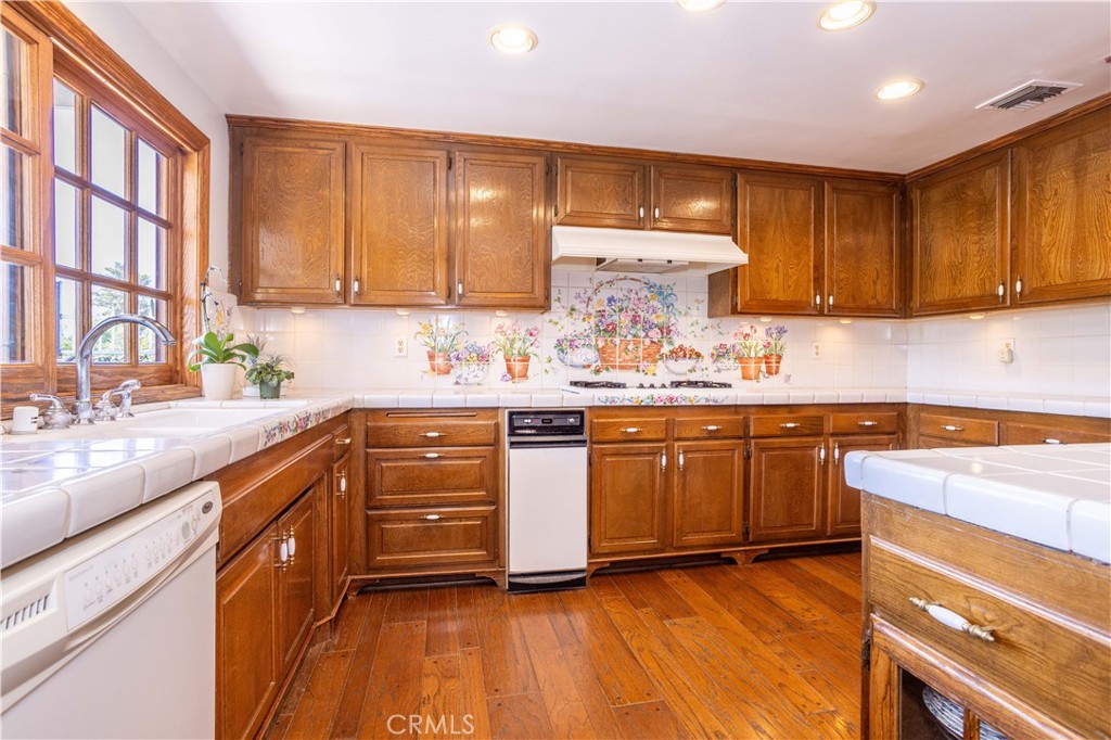 18924 Granada Circle Porter Ranch, CA 91326 - Photo 12 of 45 a kitchen with kitchen island granite countertop wooden cabinets and white appliances