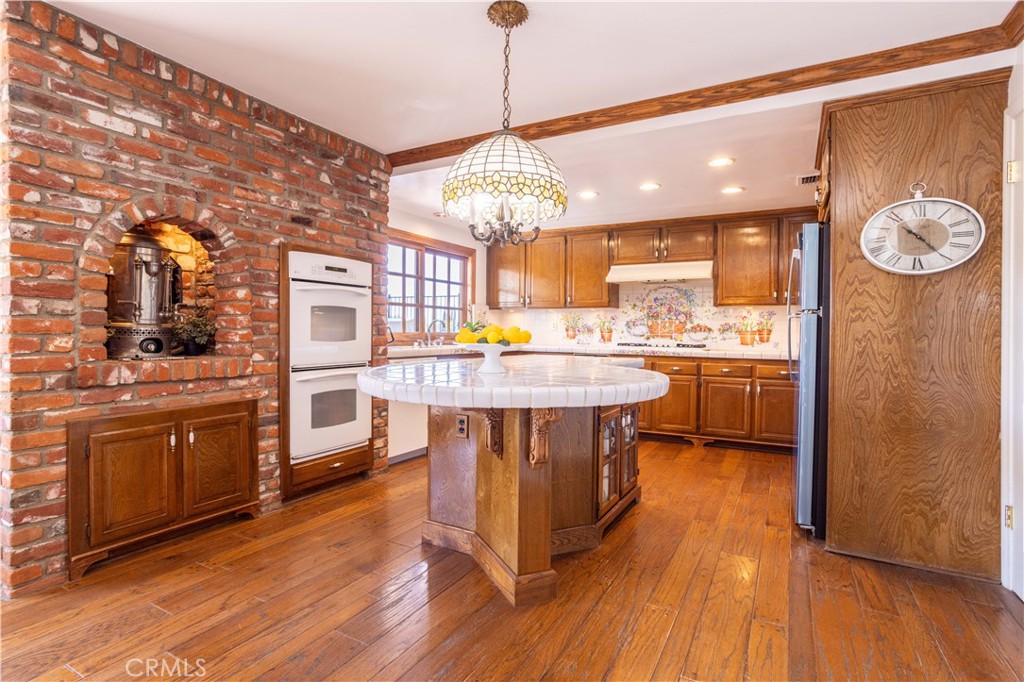 18924 Granada Circle Porter Ranch, CA 91326 - Photo 10 of 45 a kitchen with stainless steel appliances granite countertop a stove a sink dishwasher and a dining table with wooden floor