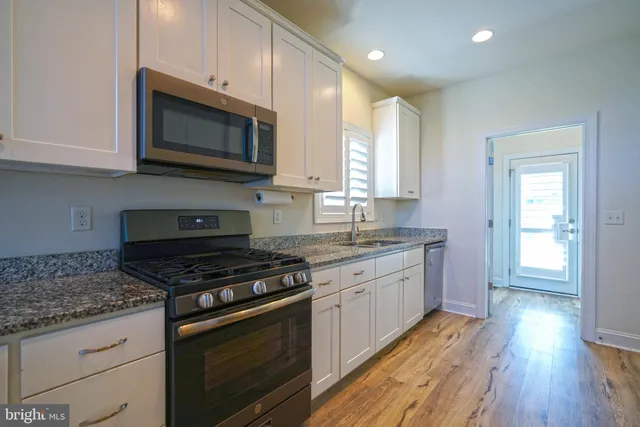a kitchen with stainless steel appliances granite countertop a stove a sink and a microwave