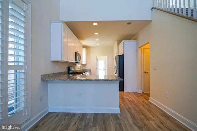 a kitchen with stainless steel appliances granite countertop a sink cabinets and wooden floor