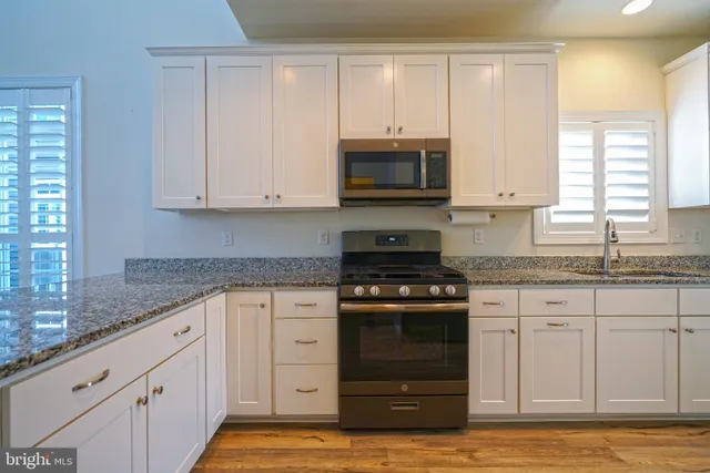 a kitchen with granite countertop white cabinets and a stove top oven