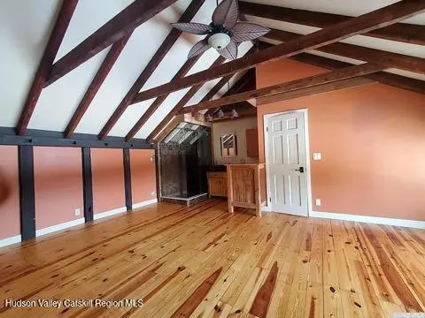 a view of an empty room with wooden floor and windows