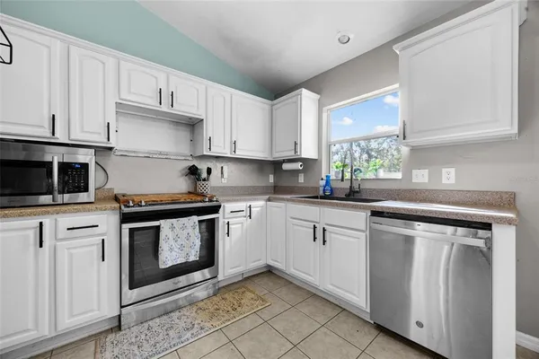 a kitchen with granite countertop white cabinets stainless steel appliances and a window
