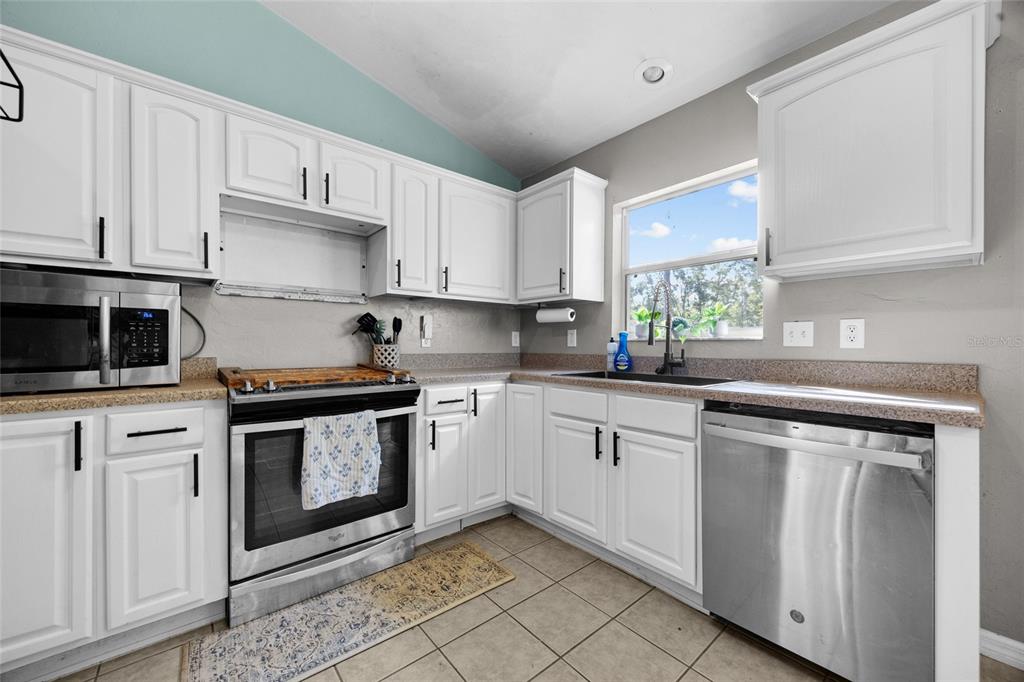 470 Margaret Street Bronson, FL 32621 - Photo 6 of 22 a kitchen with granite countertop white cabinets stainless steel appliances and a window