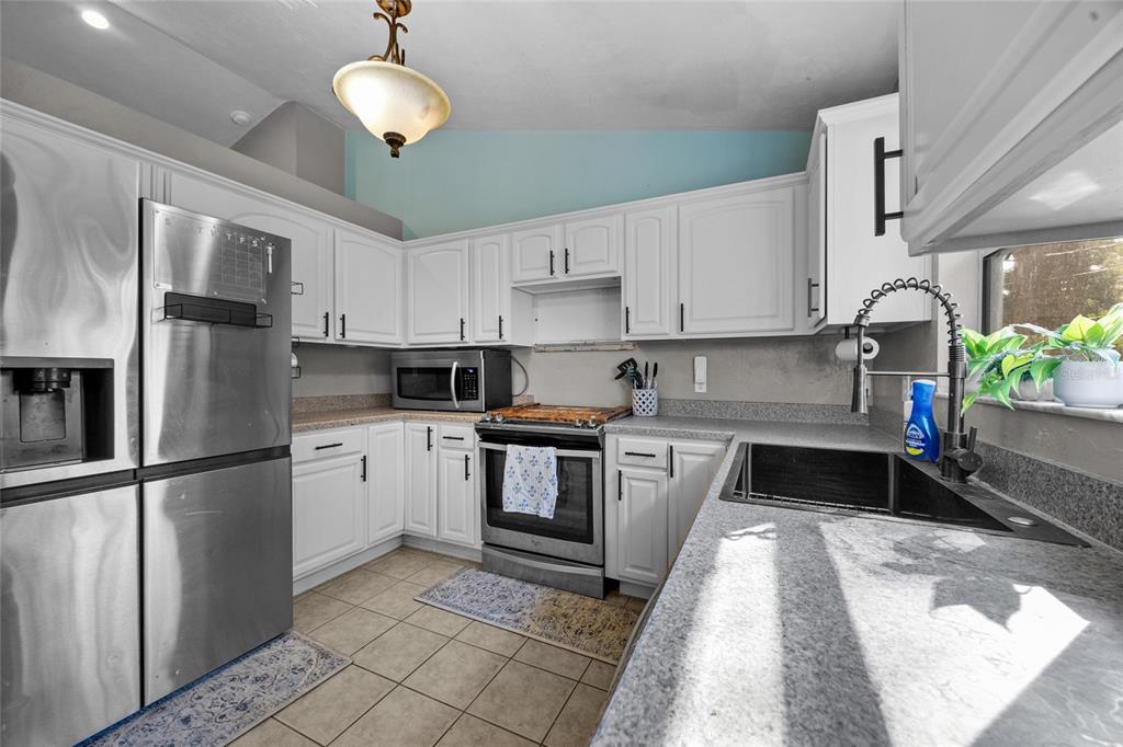 470 Margaret Street Bronson, FL 32621 - Photo 7 of 22 a kitchen with granite countertop a refrigerator a stove a sink dishwasher and white cabinets with wooden floor