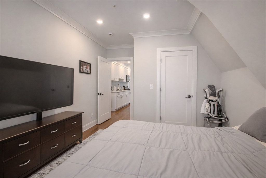 53 Quint Avenue, Unit 3 Boston, MA 02134 - Photo 9 of 18 a bedroom with a bed and a flat tv screen on dresser