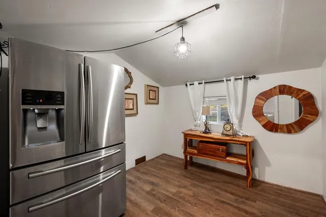 a kitchen with granite countertop a refrigerator and a wooden floor