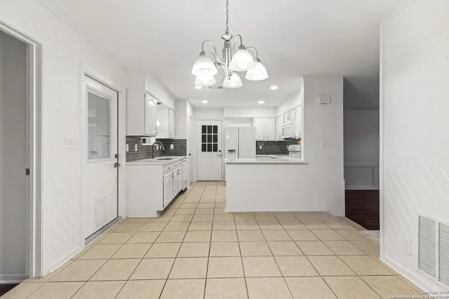 a large white kitchen with a refrigerator a stove top oven and cabinets