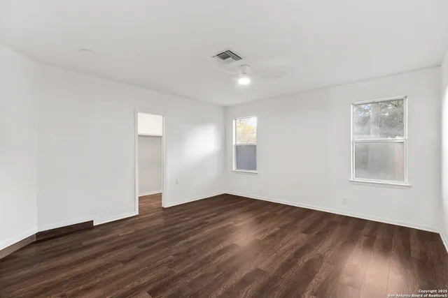 an empty room with wooden floor and windows