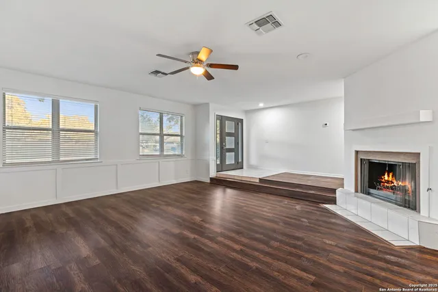 a view of an empty room with window and wooden floor