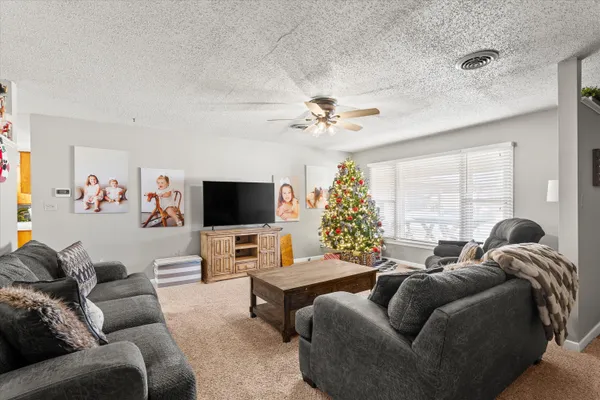 a living room with furniture ceiling fan and a flat screen tv