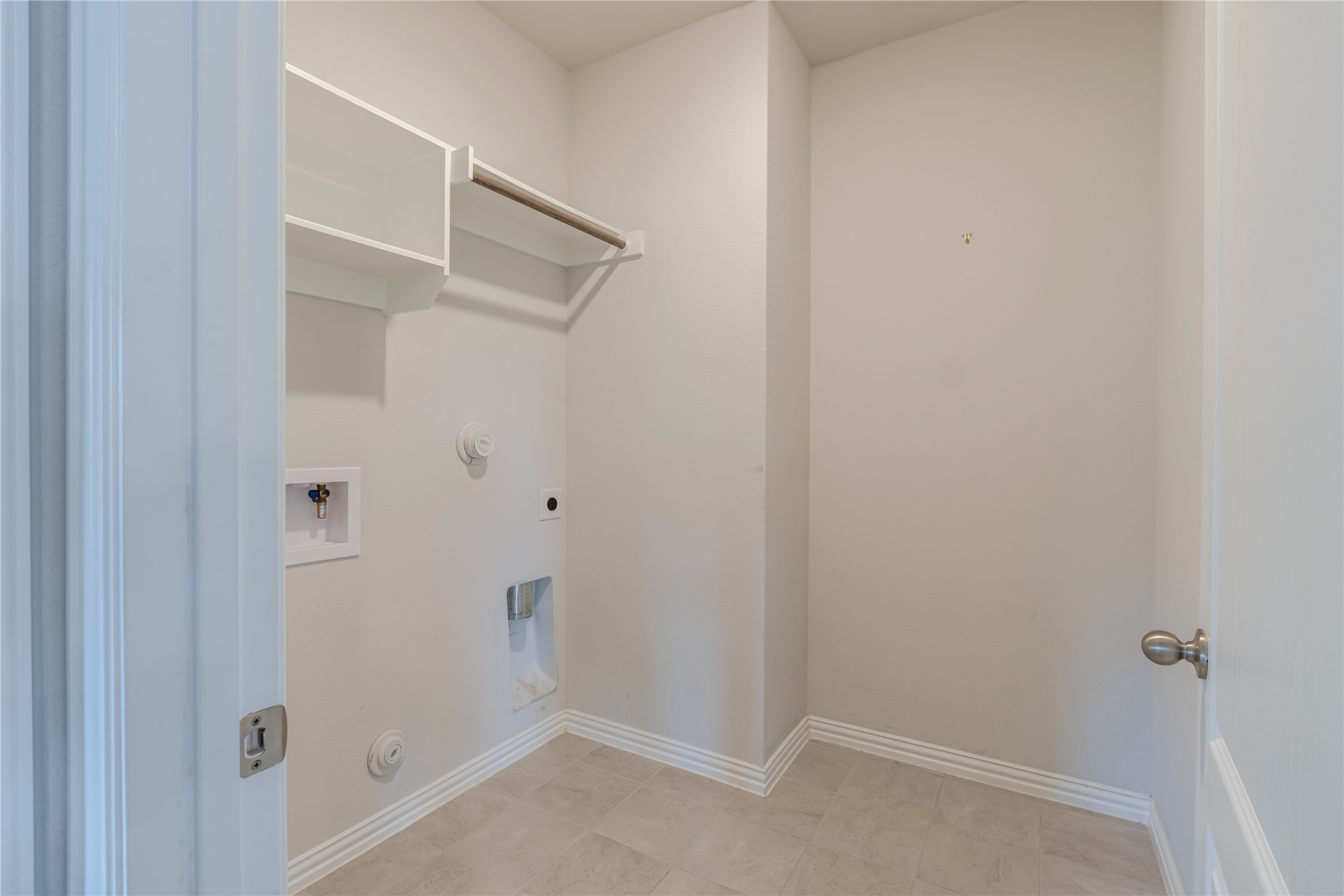 1117 Terrace View Georgetown, TX 78628 - Photo 24 of 25 Dedicated utility space featuring built-in shelving, a clothes hanging rod, and light-toned tile flooring