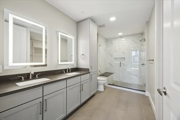 a bathroom with a double vanity sink toilet mirror and windows