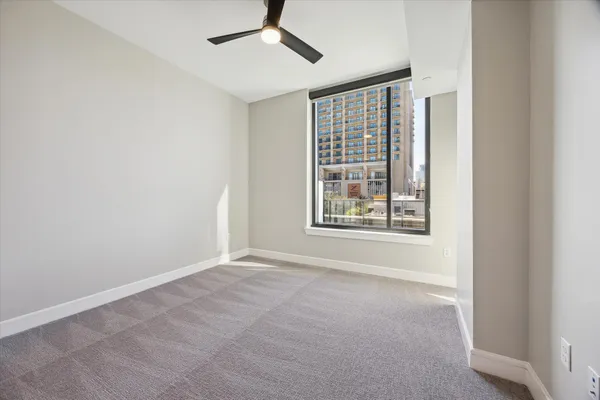 an empty room with windows and fan