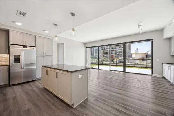 a kitchen with granite countertop a refrigerator a sink a stove and wooden floor