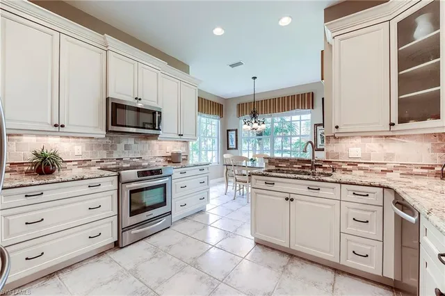 a kitchen with granite countertop white cabinets and appliances