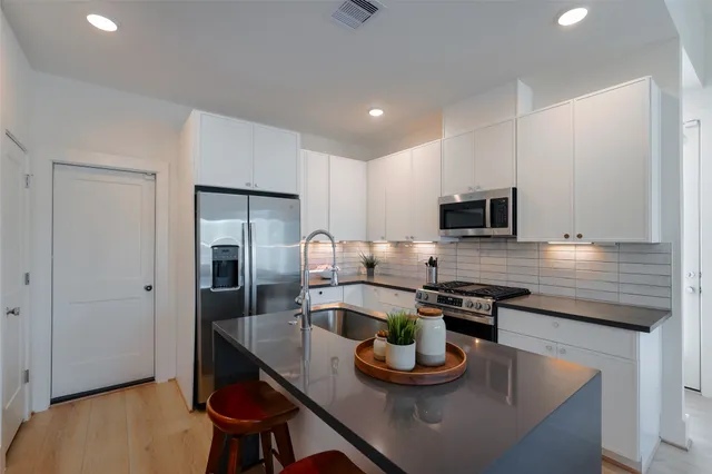 a kitchen with stainless steel appliances granite countertop a sink a stove and wooden floor