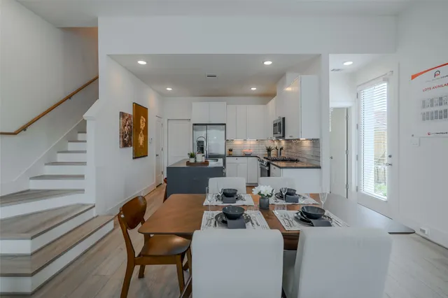 a room with stainless steel appliances kitchen island granite countertop a sink a stove a refrigerator and cabinets