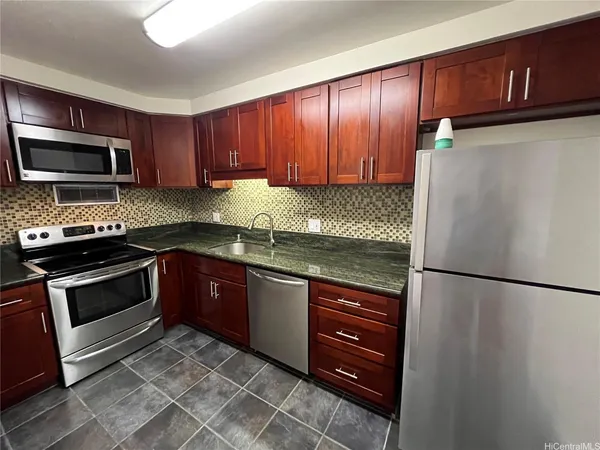 a kitchen with granite countertop wooden cabinets and stainless steel appliances
