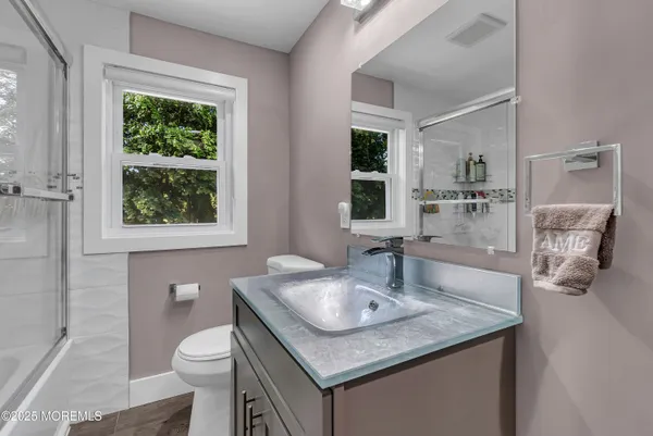 a bathroom with a granite countertop sink a toilet a mirror and window