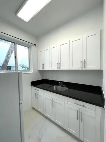 a kitchen with granite countertop white cabinets and a sink