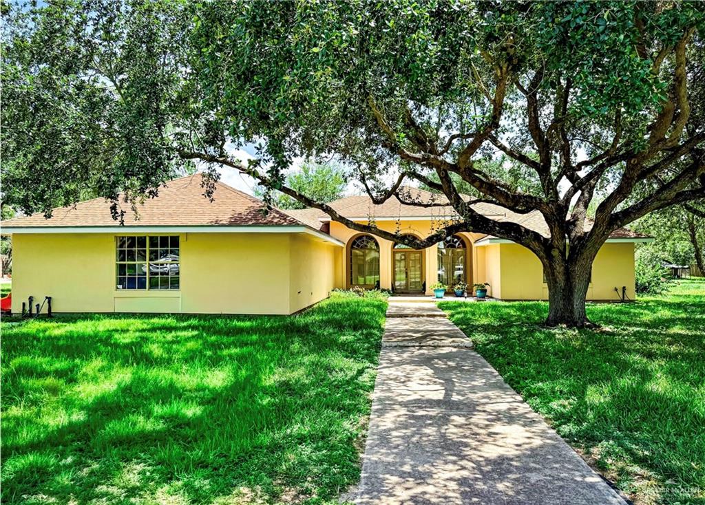 a front view of a house with a garden and tree