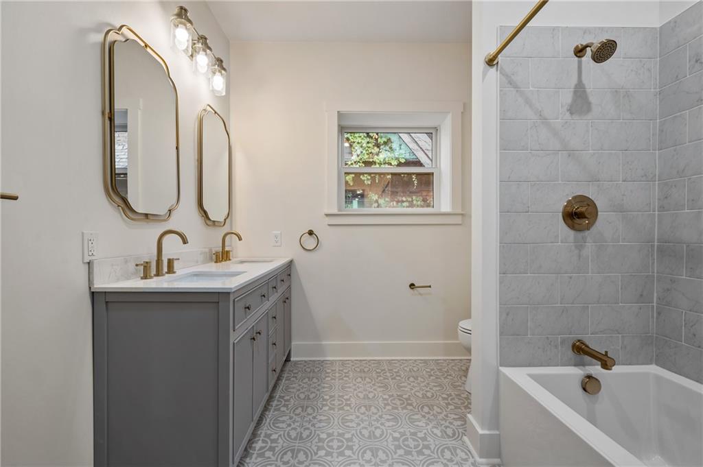 5563 Hampton Street Pittsburgh, PA 15206 - Photo 23 of 29 a bathroom with a double vanity sink a mirror and a bathtub