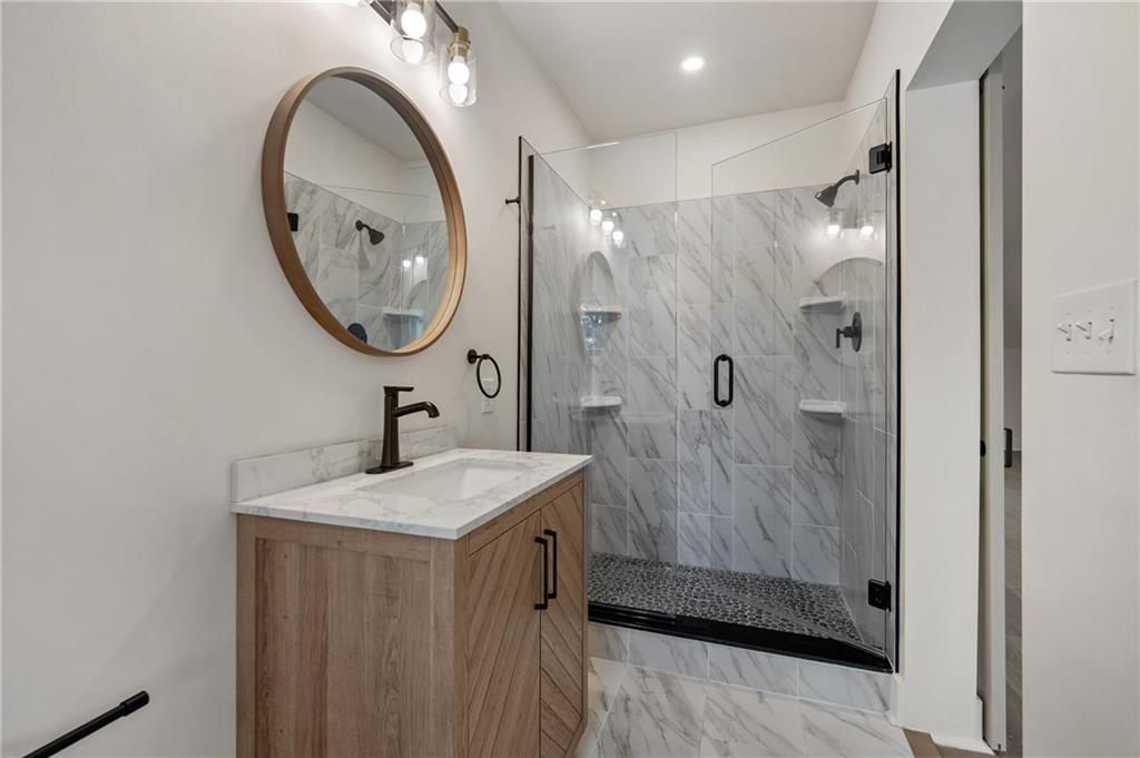 5563 Hampton Street Pittsburgh, PA 15206 - Photo 26 of 29 a bathroom with a granite countertop sink a mirror and shower