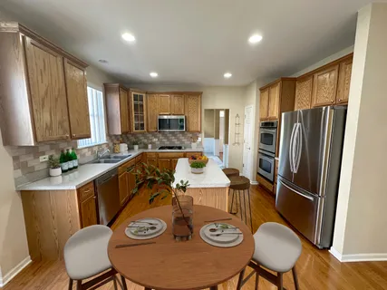 a large kitchen with stainless steel appliances a refrigerator a sink dishwasher a stove and white countertops with wooden floor