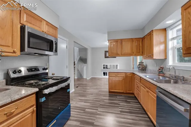 a kitchen with stainless steel appliances granite countertop a stove top oven a sink dishwasher and a microwave oven with wooden floor