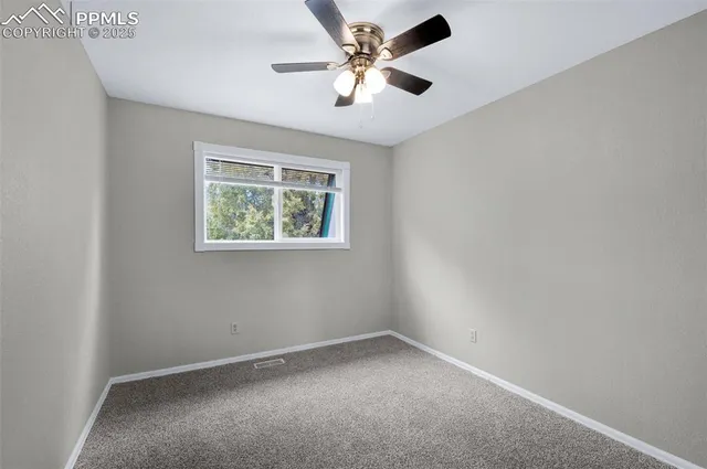 an empty room with chandelier fan