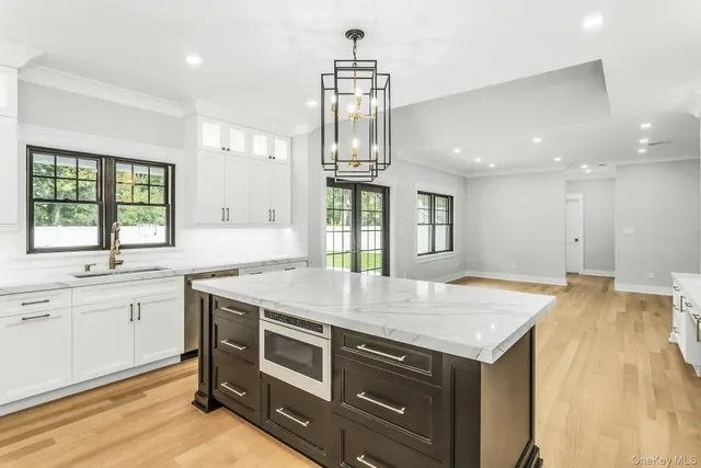 a large white kitchen with kitchen island a sink stainless steel appliances and cabinets