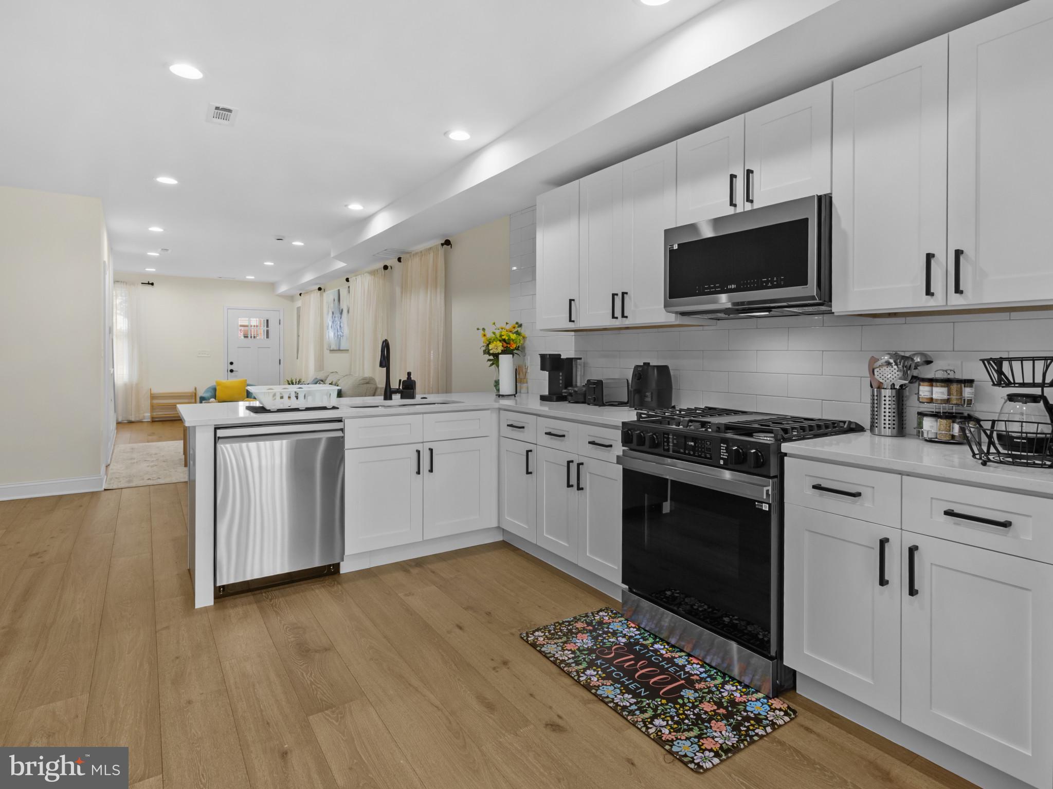1834 Providence Street Northeast Washington, DC 20002 - Photo 6 of 25 a kitchen with stainless steel appliances white cabinets a sink a stove a microwave and wooden floors