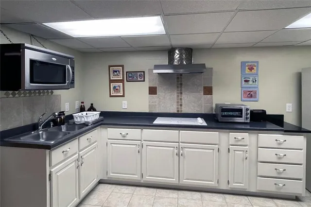 a kitchen with white cabinets and sink