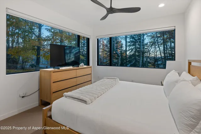 a bedroom with a bed and large windows