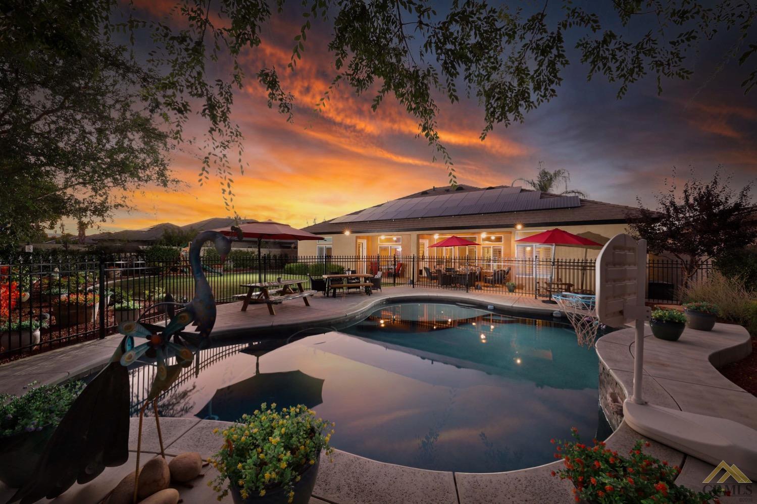 Undisclosed Address Bakersfield, CA 93314 - Photo 2 of 31 a view of a patio with couches table and chairs under an umbrella with a fire pit
