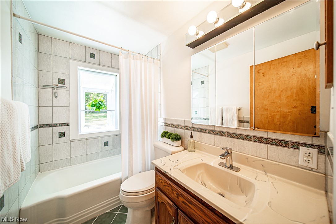 34505 Cannon Road Solon, OH 44139 - Photo 11 of 34 Full bathroom featuring shower / tub combo with curtain, oversized vanity, mirror, tile walls, backsplash, and light tile floors