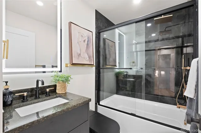 a bathroom with a granite countertop sink a toilet and shower