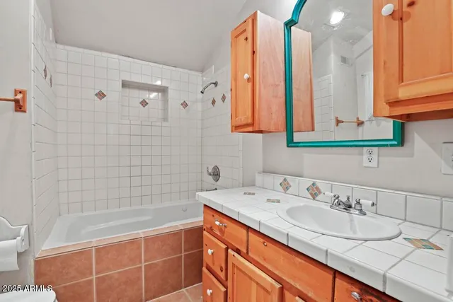 a bathroom with a granite countertop sink a mirror and a bathtub