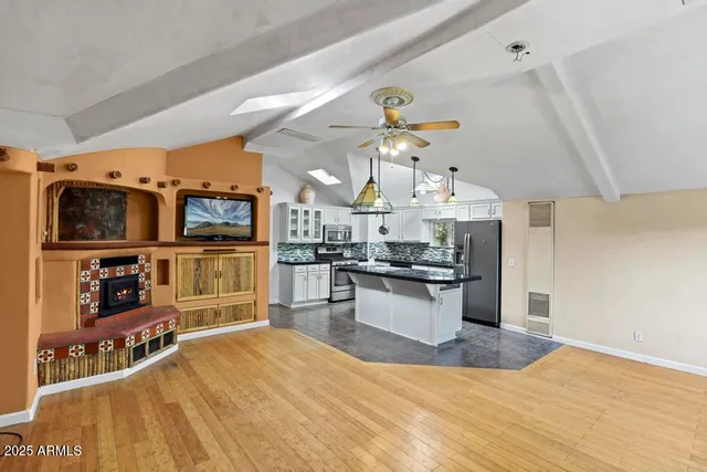 a open kitchen with stainless steel appliances kitchen island granite countertop a sink cabinets and wooden floor