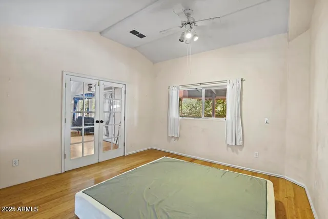 a view of a bedroom with wooden floor and windows