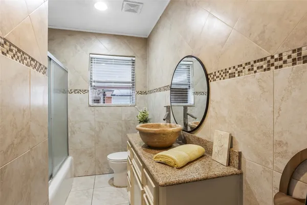 a bathroom with a granite countertop sink a toilet and shower