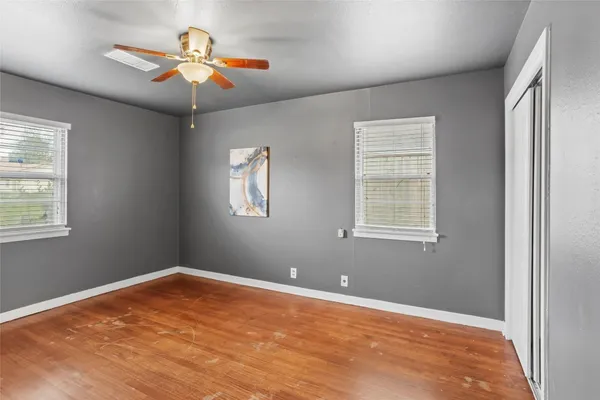 an empty room with a chandelier fan and windows