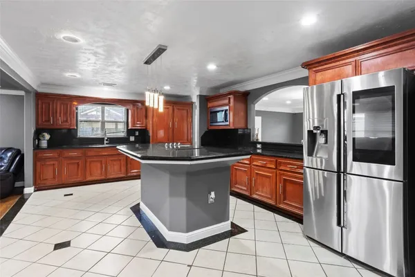 a large kitchen with stainless steel appliances kitchen island granite countertop a refrigerator and a stove top oven